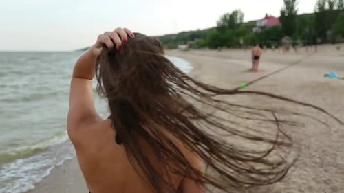 Joven y juguetona mujer risueña corre junto al mar en una playa tropical durante la puesta de sol y mira hacia atrás
