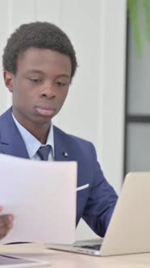 African Businessman Celebrating Success while Reading Documents in Office, Vertical Video