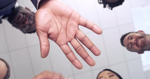 Team, unity and fun at an office, business group joining hands from below