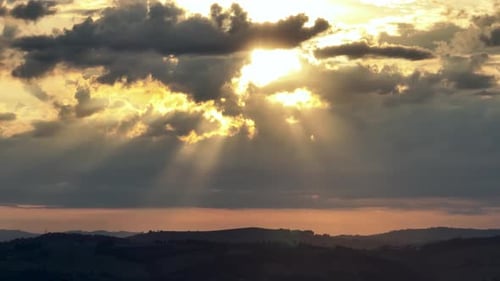 Sunset at rural life scene. Sun rays between clouds at sunset sky.