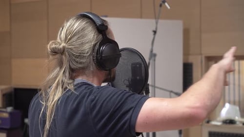 Mann singt durch einen Popfilter zum Kondensatormikrofon, Stimme aufnimmt, Nahaufnahme von hinten