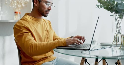 Young Adult Typing on Laptop at Glass Table