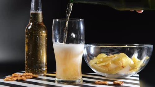 Gekühltes Bier gießt in Glas vor dunklem Hintergrund