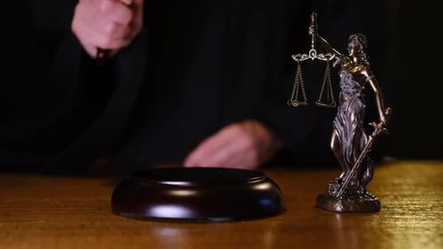 Closeup Composition of a Wooden Gavel and Bronze Lady Justice Statue on a Judge Desk