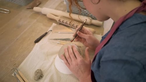 Woman working in pottery studio workshop making bowl from clay.