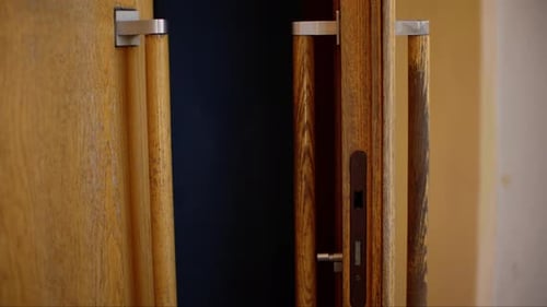Closeup of Partially Opened Wooden Door with Brass Handle Revealing Dark Interior