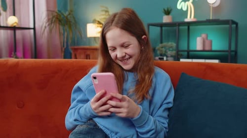 Smiling Girl Using Pink Smartphone on Couch