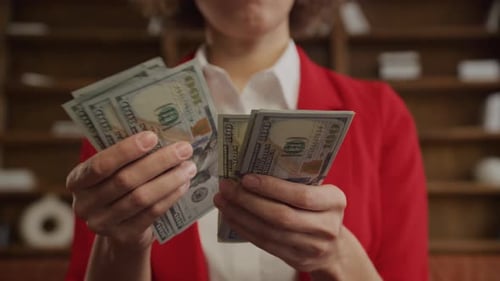 Person Counting Stacks of One Hundred Dollar Bills