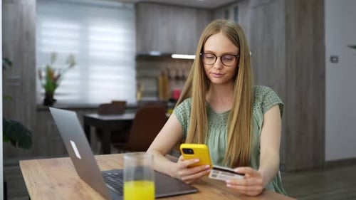 Junge Frau nutzt Smartphone und Kreditkarte für Online-Einkäufe zu Hause