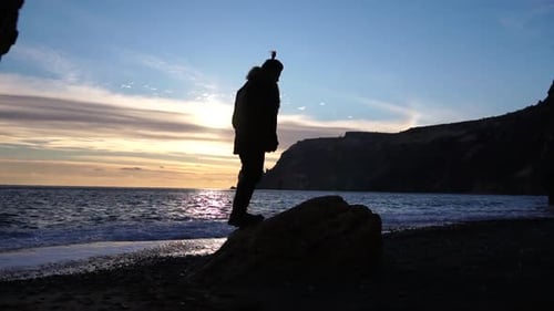 Un atleta masculino dio un salto mortal hacia atrás y aterrizó de pie en la playa, vista lateral en cámara lenta