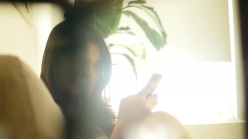 Woman Relaxing at Home Using a Smartphone