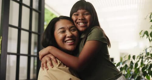 Smiling Woman and Girl Embrace Affectionately Indoors