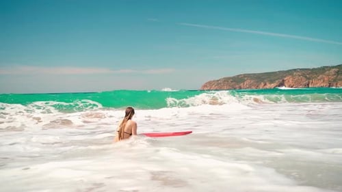 Playful Surfer Girl on Seashore As Waves Splashes Over at Scenic Beach