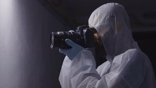 Forensic photographer taking photos, looking into camera, front face middle shot