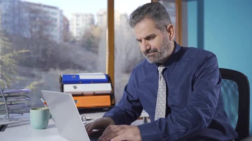 Adult man working in office working on laptop.