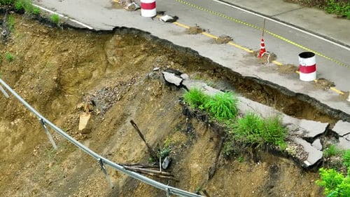 Landslide damage and fractured road surface seen from above.