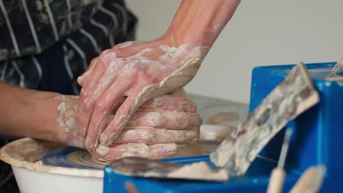 Une potière travaille sur un tour de potier et fabrique un pot en céramique en argile dans un atelier de poterie.