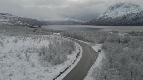 Driving through a desolate snowy winter landscape with huge mountains and fjord