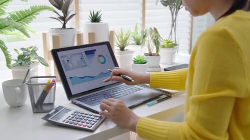 Woman Analyzing Data at Bright Desk with Plants