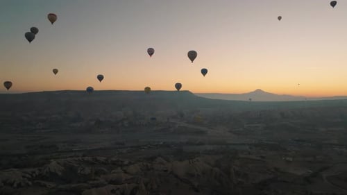 Drone view of hundreds of colorful hot air balloons soaring at sunrise in Cappadocia