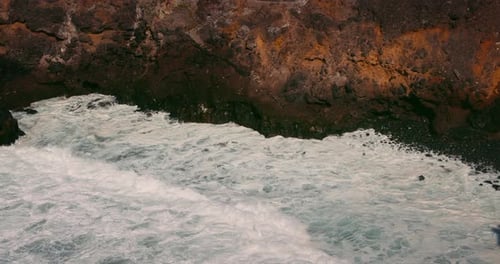 Azure Ocean and Giant Waves Crashing at Rocky Cliff with Splashing and White Sea Foam