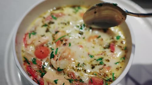 Close up of a spoon lifting shrimp from a creamy seafood soup