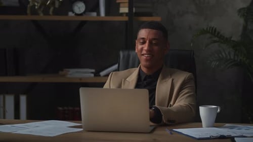 Smiling Man Works at Laptop in Modern Office
