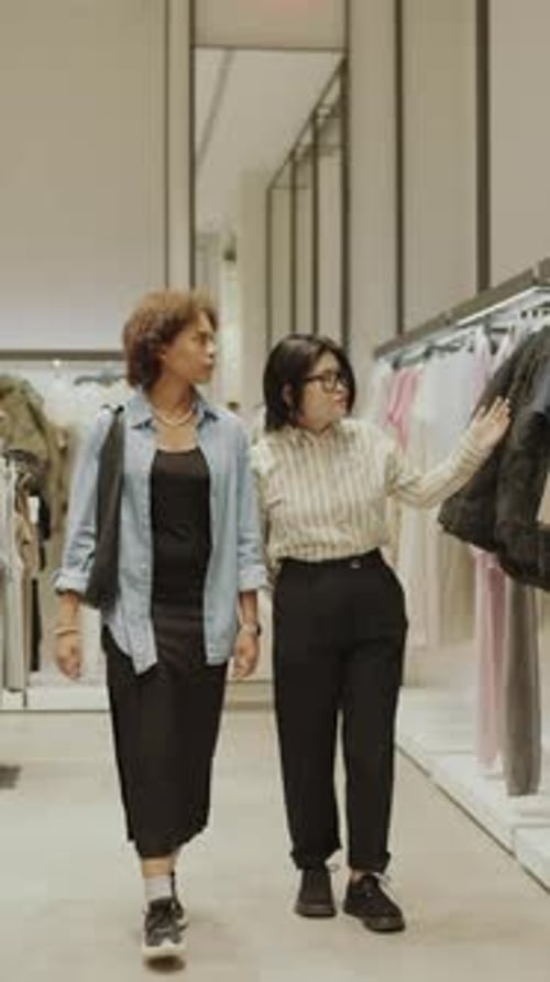 Female Shop Consultant Showing Customer around Designer Boutique