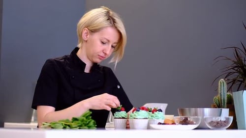 Woman Decorating Cupcakes with Berries and Mint