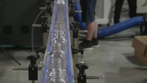 Moulded plastic PET bottles are moving on a conveyor belt