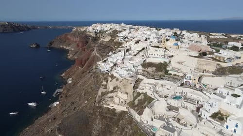 Aerial shot of a whitewashed city on a mountain by the sea against the sky