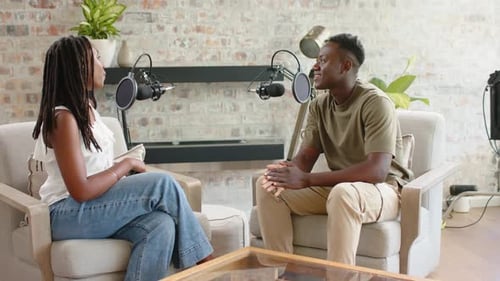 Un Afro-Américain coanime la lecture d'une invite sur smartphone et enregistre un podcast en studio avec des micros