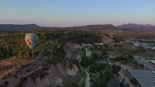 Hot Air Balloon Floating Over Rural Landscape at Sunrise