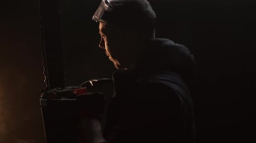 Man with Chainsaw in Dark and Smoky Setting