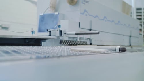Ein Stück Sperrholz rollt aus einer Maschine für die Möbelfertigung. Automatisierte Bauindustrie