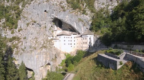Drone shot over Predjama near Predjama Castle, connected to Postojna cave. Pulling in on the castle