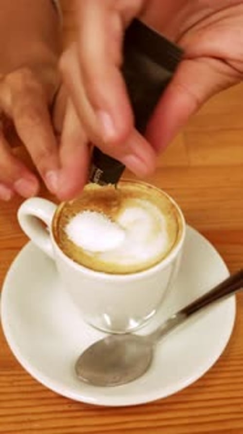 Person Pouring Sugar and Stirring Coffee