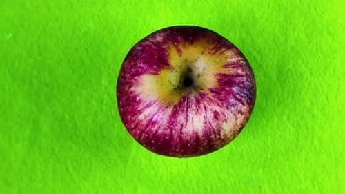 Rotating apple on vibrant green background, showing healthy food and natural motion