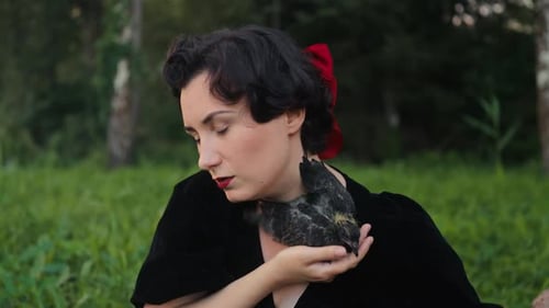 Uma mulher elegante segurando graciosamente um pássaro em um belo cenário natural cercado por naturezas