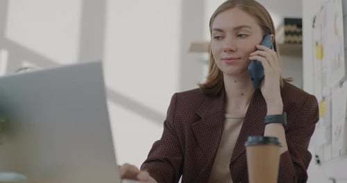 Woman Working on Laptop and Talking on Phone