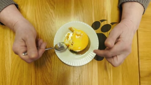 Person Holding a Kitchen Utensil Over a Dish of Food on a Yellow Plate
