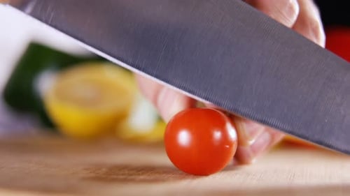 Fresh Tomato Being Cut in Half on Wood