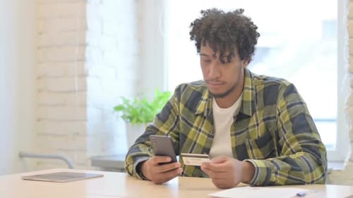 Young Man Using Phone and Credit Card