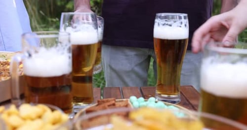 Foamy Beers and Snacks on a Wooden Table