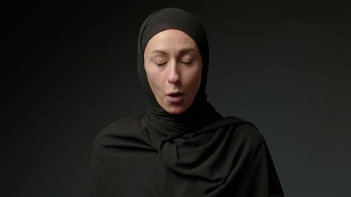 Une femme surprise et excitée en hijab choquée par une offre incroyable isolée sur fond noir