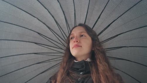 Woman Under Umbrella Looks Upward on a Cloudy Day