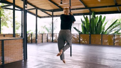 Male Pole Dancer Performing Acrobatic Routine in Studio