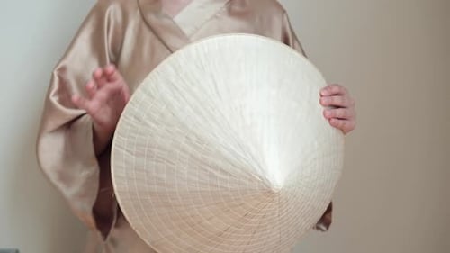 Young Adult Displaying Asian Conical Hat Indoors