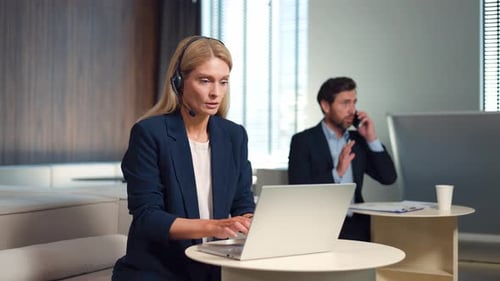 Two Caucasian Business People Using Laptop and Smartphone for Work at Office