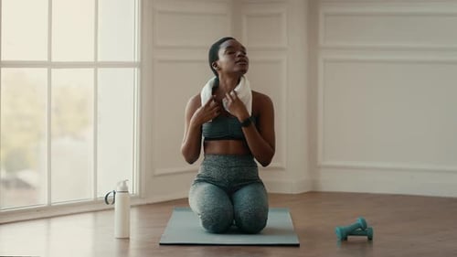 Woman Wipes Face with Towel After Home Workout